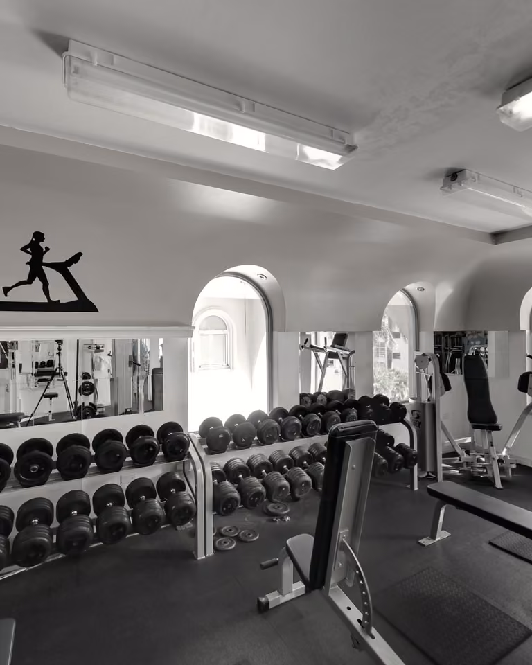 Dumbbell racks under three arched windows in the free-weight room at IFM.