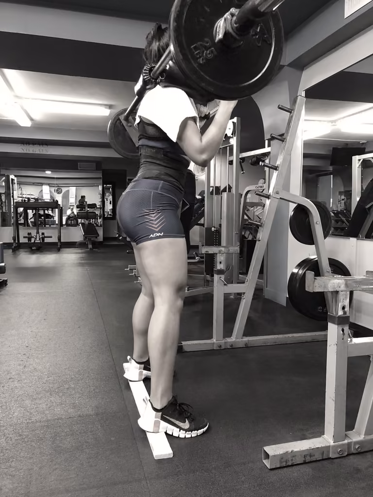 A member squatting under a loaded barbell in the rack at IFM.